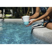 Une femme tient un désinfecteur d''eau de piscine au bord de la piscine