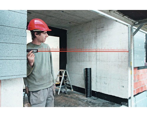 Ein Bauarbeiter verwendet ein digitales Messgerät mit Laser im Rohbau.