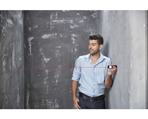 Mann benutzt Laser-Entfernungsmesser im Raum