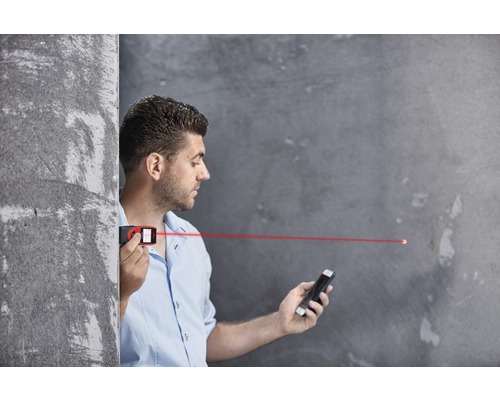 Mann benutzt einen Laser-Entfernungsmesser und ein Smartphone zur Messung.