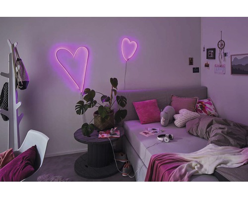 Chambre avec lit, plante et néons en forme de cœur comme décoration