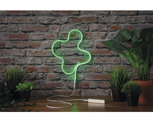 Lampe néon décorative en forme de trèfle devant un mur de briques