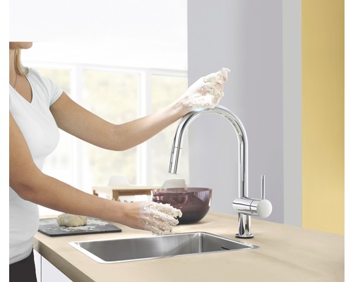 Küchenszene mit Spültischarmatur und Frau beim Teig kneten