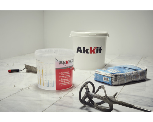 Scène de pose de carrelage avec outils, colle et seau AkKit