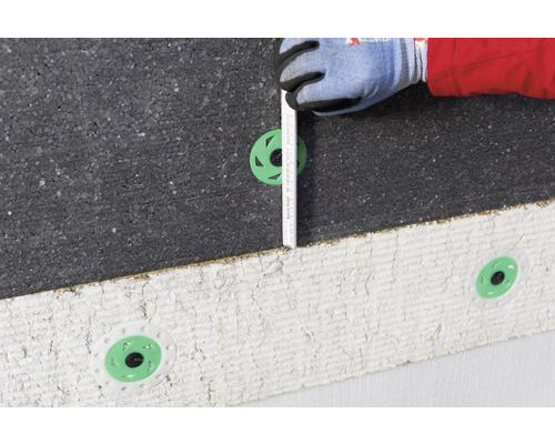 Une personne mesure un panneau isolant avec une règle