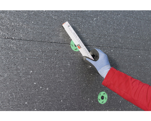 Personne mesurant un panneau isolant avec un mètre pliant