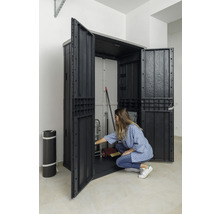 Offener Geräteschrank aus Kunststoff mit Lagergegenständen und einer Person, die sich davor befindet.