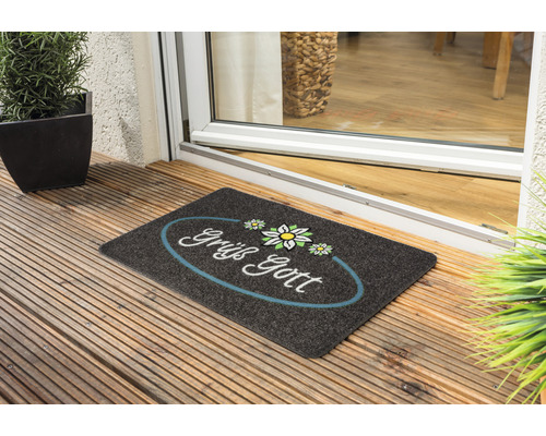 Fußmatte mit dem Aufdruck ''Grüß Gott'' vor einer Haustür.