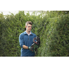 Mann schneidet Hecke mit Akku Heckenschere im Garten.