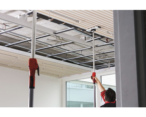 Montage de plaques de plafond avec outil de montage dans une pièce avec construction de plafond.
