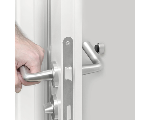 Main ouvrant une porte blanche avec ferrures en acier inoxydable