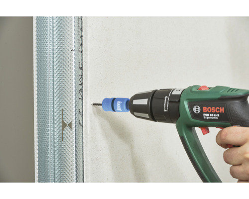 Ein Mann verwendet einen Akkuschrauber von Bosch, um eine Schraube in eine Gipskartonwand einzuschrauben. Die Wand wird von einem Metallprofil gehalten.