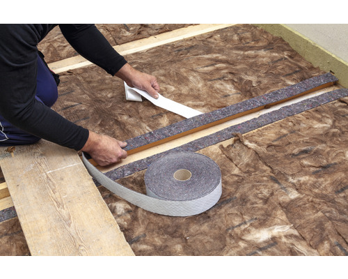 Handwerker befestigt Dichtband auf Dämmwolle und Holzrahmen für die Isolierung