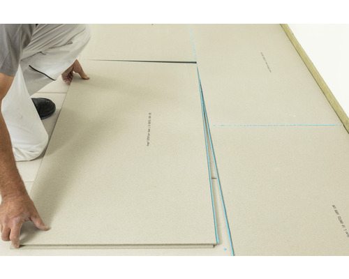 Un homme pose des plaques de chape sèche sur le sol