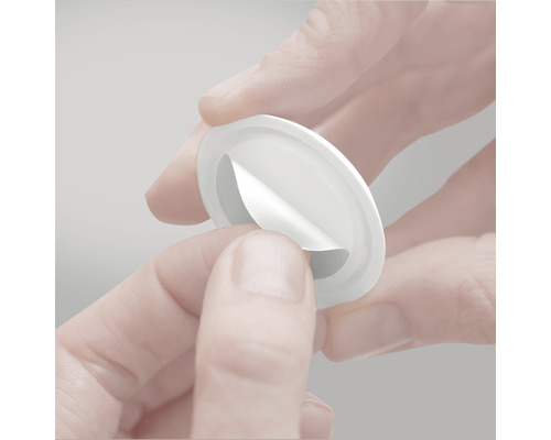 Une main retire le film protecteur d''un bouton de meuble.