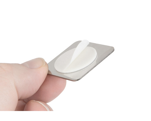 Metallschild mit Klebepad in der Hand