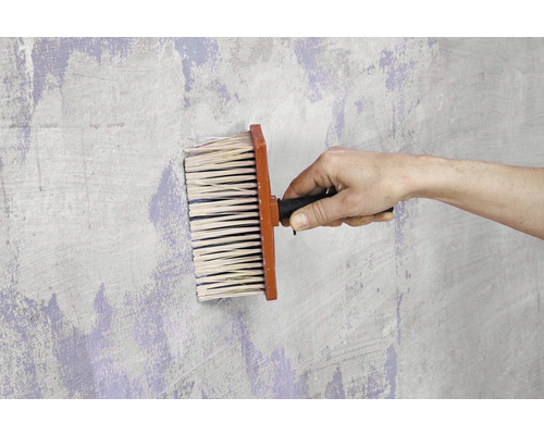 Brosse à tapisser en cours d''utilisation sur un mur.