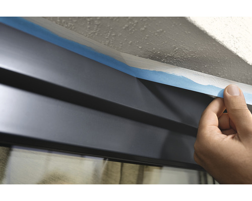 Application de ruban de masquage sur une vitre avant des travaux de peinture.