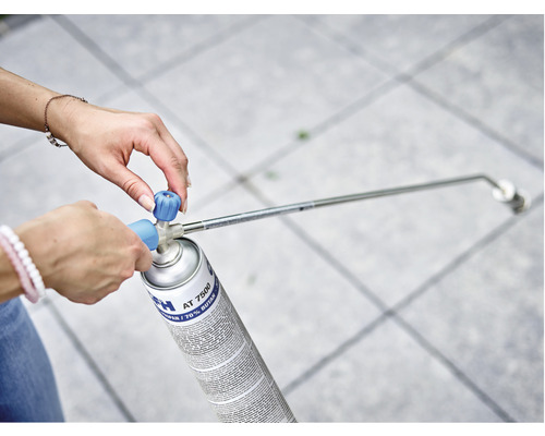 Frau befestigt Brenneraufsatz auf einer Gasflasche