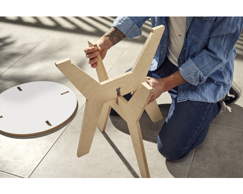 Personne assemblant une table en bois avec un plateau de table rond