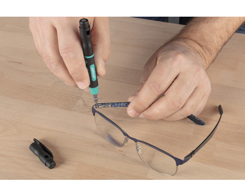 Une personne répare des lunettes avec un tournevis de précision.
