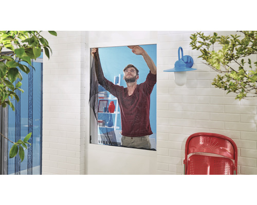 Mann befestigt Insektenschutzgitter am Fensterrahmen für Insektenschutz.