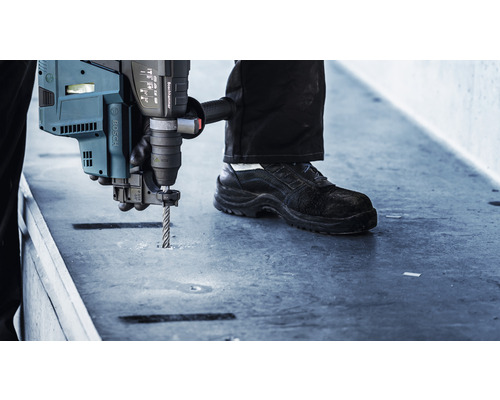 Un utilisateur perce un trou dans une surface avec un perforateur.