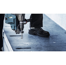 Un homme perce une surface avec un perforateur.