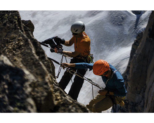 Deux alpinistes avec casques et cordes grimpent sur un rocher.