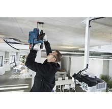 Ein Mann bohrt mit einer Bohrmaschine ein Loch in die Decke in einem Büro