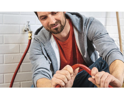 Mann repariert einen undichten Wasserschlauch in einem Raum