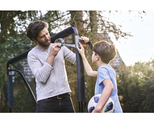 Vater und Sohn reparieren ein Fussballtor mit Klebeband