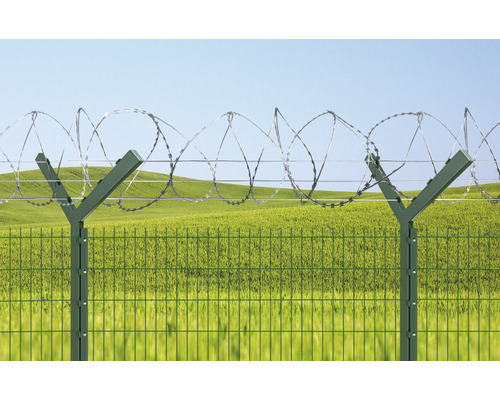 Zaun mit Stacheldraht vor grüner Landschaft