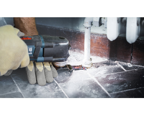 Une personne utilise un outil multifonction près d''un radiateur.