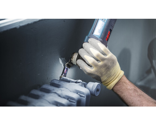 Artisan travaillant sur un tuyau de chauffage avec une scie oscillante