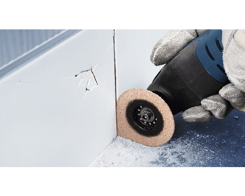 Une personne utilise un outil multifonction pour enlever les joints de carrelage endommagés.