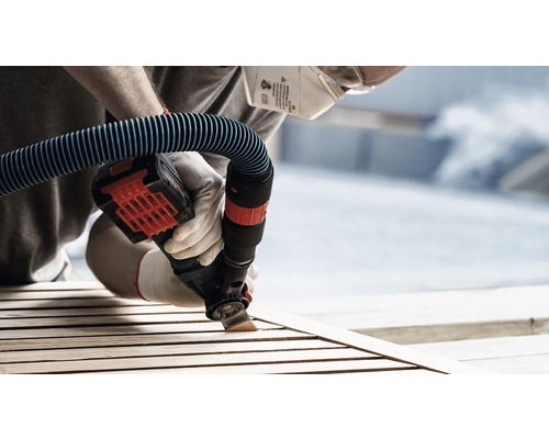 Personne ponçant du bois avec un outil électrique avec raccord d''aspirateur, masque de protection et gants