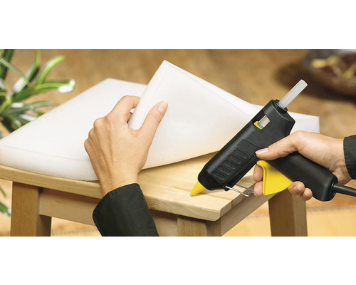 Heissklebepistole beim Anbringen von Schaumstoff auf einem Holzstuhl