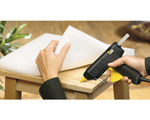 Heissklebepistole beim Verkleben von Schaumstoff auf einen Holzstuhl