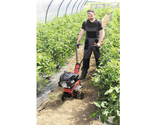 Mann arbeitet mit einer Gartenfräse in einem Gewächshaus.
