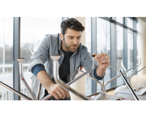 Ein Mann montiert einen Tisch mit Metallbeinen und Bodenschonern