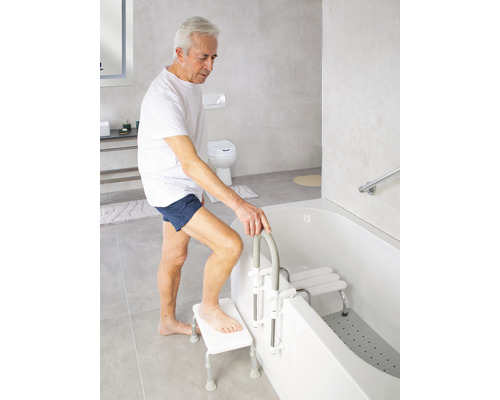 Un homme utilise un élévateur de bain et un siège de bain dans une salle de bain lumineuse.