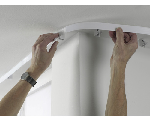Une personne installe un rail de rideau au plafond