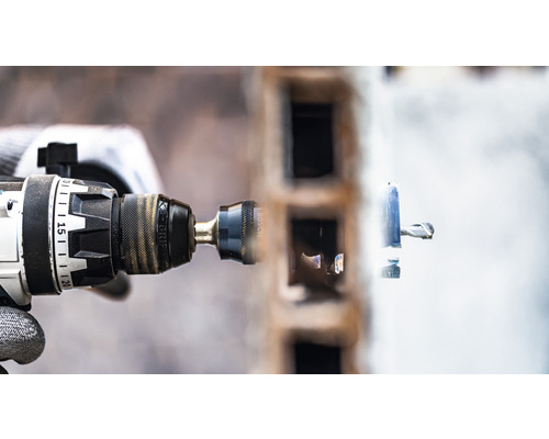 Une perceuse perce un trou dans un mur.