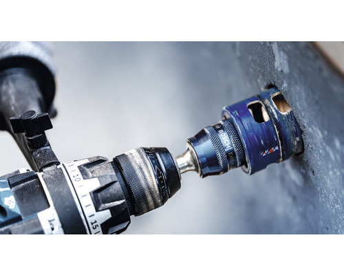 Perceuse avec scie cloche perçant un trou dans un mur