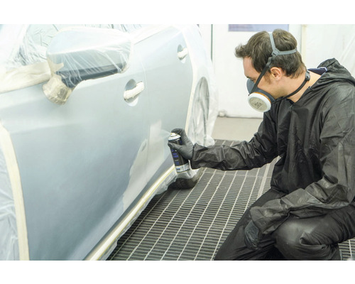 Homme peignant une voiture avec une bombe aérosol