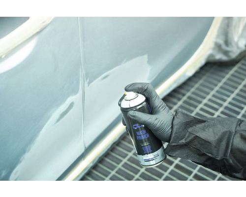 Une personne applique un apprêt wash sur une portière de véhicule avec un aérosol.