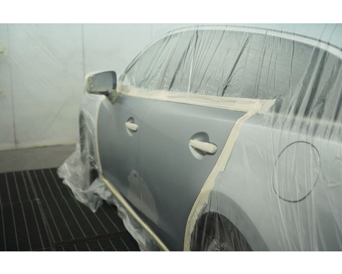 Voiture en préparation pour la peinture, protégée par du ruban de masquage et du film