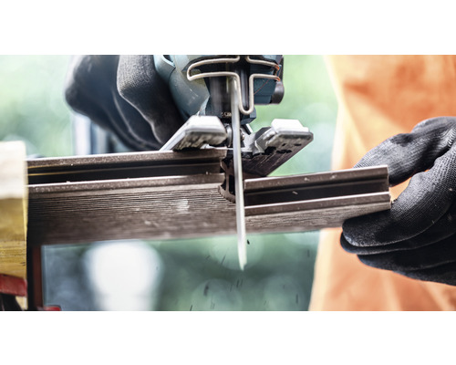 Une scie sauteuse coupe une pièce.