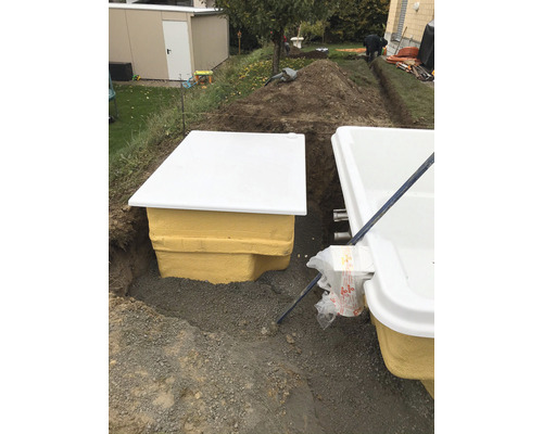 Zwei Kläranlagenbehälter sind in einem Garten in der Erde vergraben.